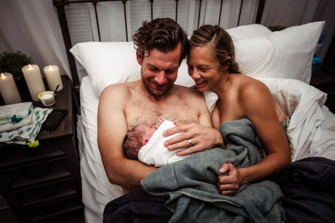 mom and dad in bed with new born baby snuggling